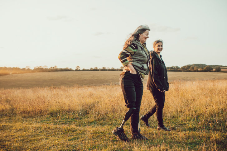 Two women walking in a field on a summer evening