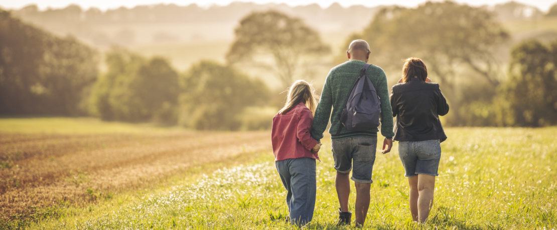 A family walking in a field on a summer evening