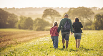 A family walking in a field on a summer evening